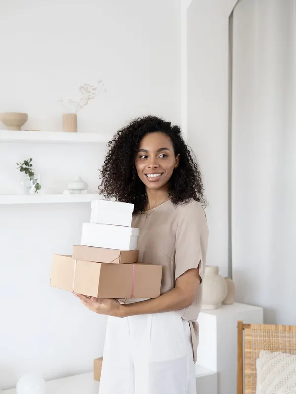 A woman holding a stack of parcels ready to ship from her home